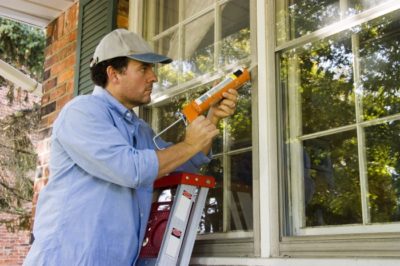Handyman chaulking a window